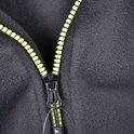 Gedetailleerde close-up van een neongele ritssluiting op een zwarte fleece trui.