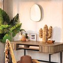 Gouden spiegel in organische vorm, hangend boven een houten bureau met accessoires.