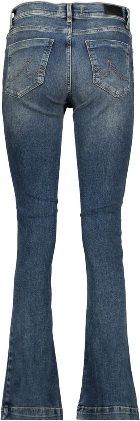 Model draagt een flared spijkerbroek in donkerblauw met subtiele slijtageplekken. De broek is vanaf de knie wijd uitlopend.