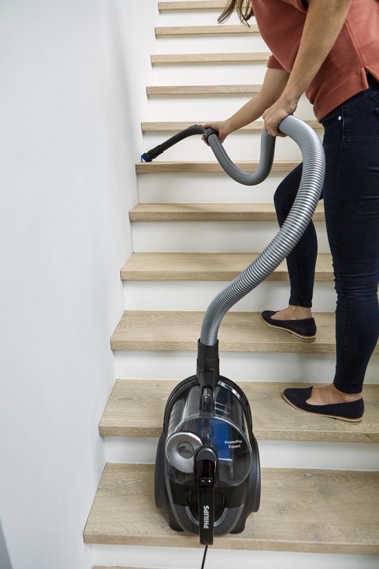 Een vrouw met een Philips stofzuiger op de trap.