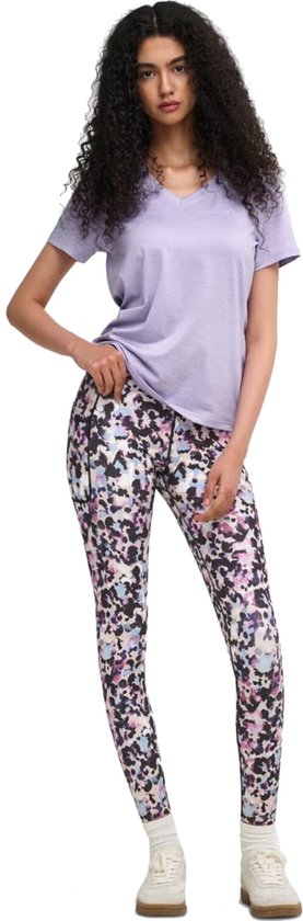 Model in paars sportshirt met V-hals en een veelkleurige legging met abstracte print. Ze houdt haar shirt op.
