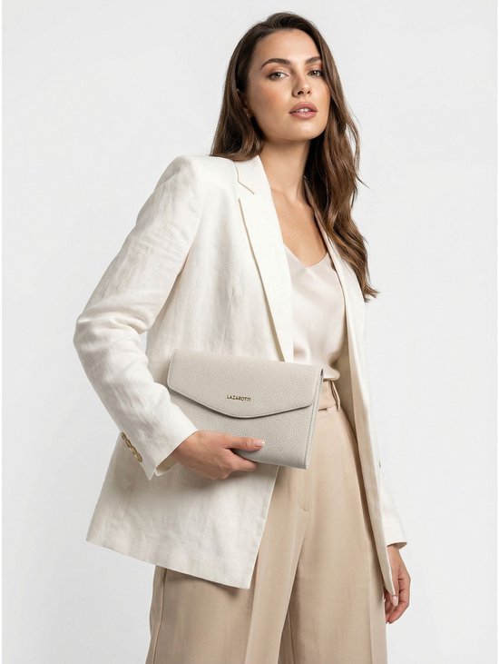 Lichtgrijze lederen clutch met goudkleurig logo, gedragen door een model met een witte blazer.