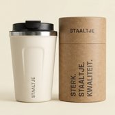 Een crème kleurige RVS beker met 'STAALTJE' logo en een bijpassende verpakking met de tekst 'STERK. STAALTJE. KWALITEIT.'.