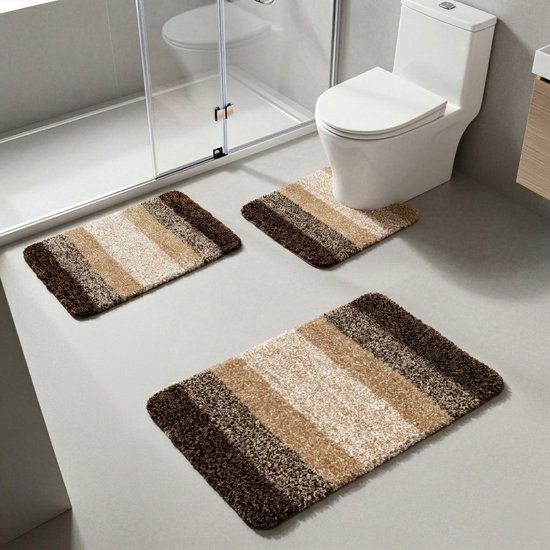 Drie bruin, beige en crème gestreepte badmatten in een badkamer bij toilet en douche.