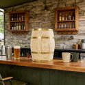 Houten vat met tapkraan op een houten bar met bier en drankjes.