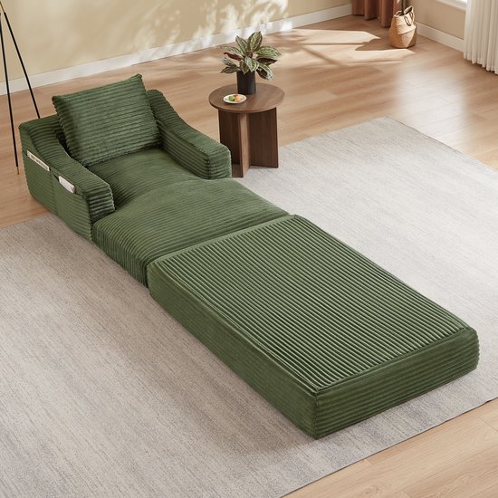 Groene corduroy fauteuil met uitklapbaar bed, in een woonkamer.