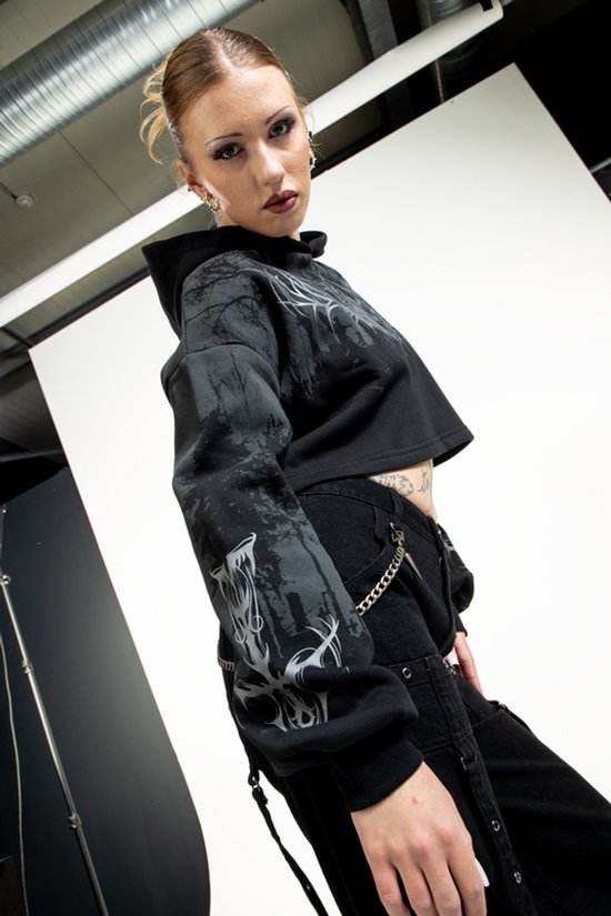Zwarte crop hoodie met grafische print van een bos en demonische kop. Model draagt de hoodie.