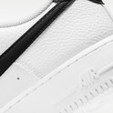 Witte Nike Air Force 1 sneaker met zwarte swoosh en getextureerd leer.