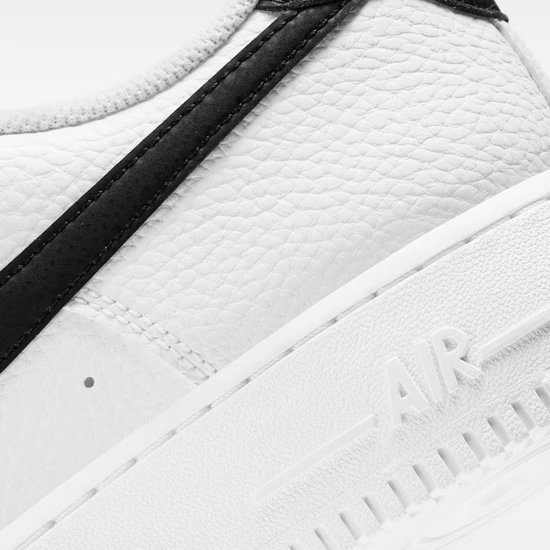Witte Nike Air Force 1 sneaker met zwarte swoosh en getextureerd leer.