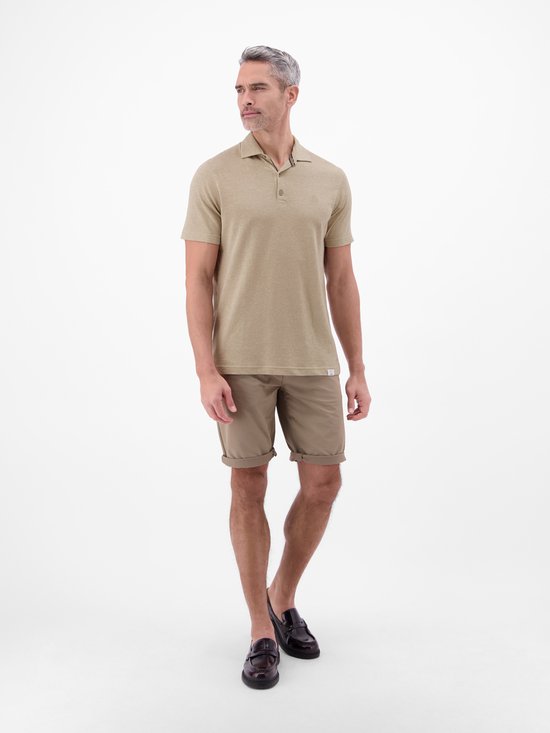 Man in een lichtbruin gemêleerd poloshirt, beige short en donkerbruine loafers.