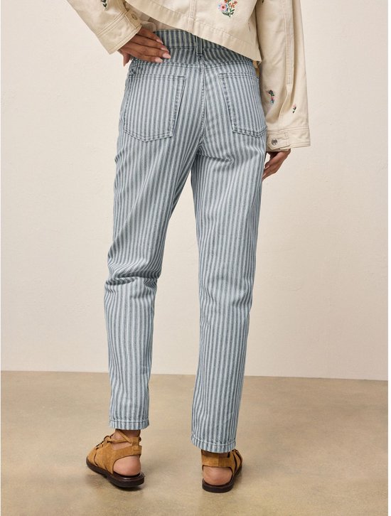 Vrouw op de rug gezien, draagt een lichtgrijs gestreepte jeans met rechte pijpen en bruine sandalen.