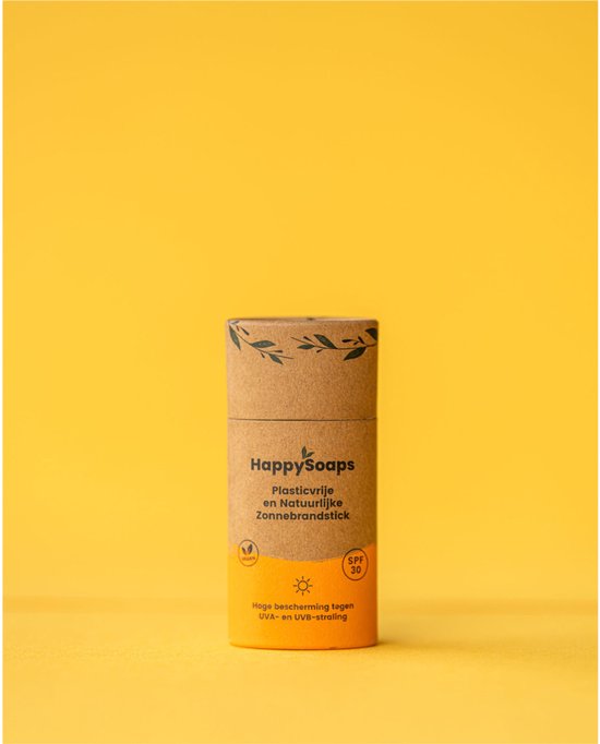 HappySoaps plasticvrije, natuurlijke zonnebrandstick in kartonnen verpakking met oranje en bruine opdruk, SPF 30, op gele achtergrond.