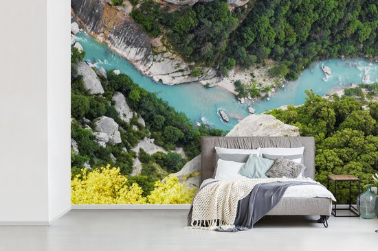 Papier peint avec une photo aérienne des Gorges du Verdon, une rivière turquoise serpente à travers une gorge verdoyante avec des rochers et des arbres.