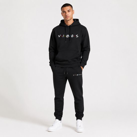 Man in een zwarte hoodie met 'VIBES' print en bijpassende joggingbroek.