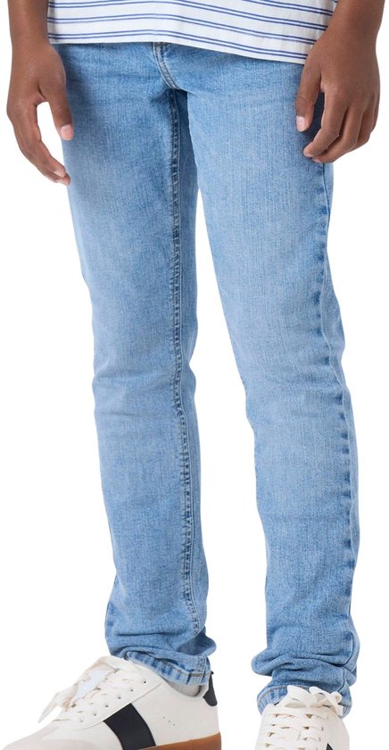 Jongens lichtblauwe slim fit jeans gedragen met gestreepte top en witte sneakers.