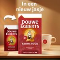 Twee pakken Douwe Egberts Aroma Rood koffie en een mok met koffie.