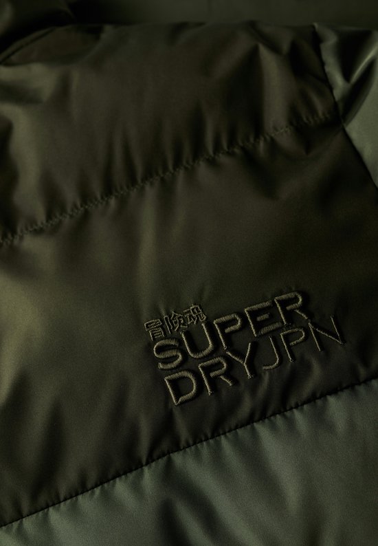 Detail van donkergroene jas met geborduurd Superdry JPN logo.