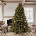 Een groene kunstkerstboom met kerstverlichting en kleine decoraties in een gezellige woonkamer.