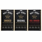 Drie zakken Smyrna Beef Jerky in de smaken Smoked, Original en Chili Sriracha, elk met de tekst '100% Gedroogd Rundvlees' en voedingswaarden.