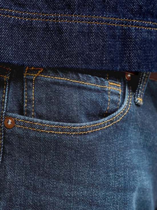 Close-up van het zakdetail van een medium blauwe jeans met contrasterende oranje stiksels.