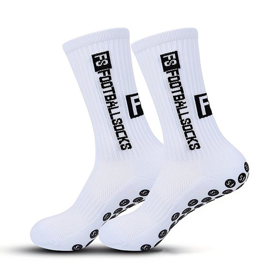 Twee witte voetbalsokken met zwarte "FS FOOTBALL SOCKS" tekst en anti-slip nopjes op de zool.