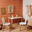 Witte kindertafel met twee witte stoelen in een kinderkamer. Houten poten, potloden op tafel.