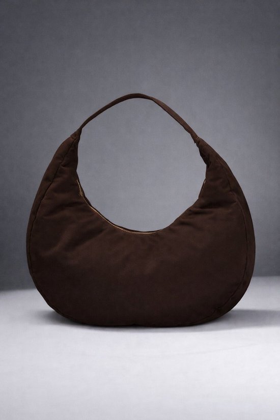 Donkerbruine suède hobo tas met gouden rits, op grijze achtergrond.
