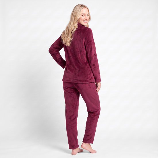 Een blonde vrouw draagt een bordeauxrood fleece huispak, bekeken vanaf de achterkant.