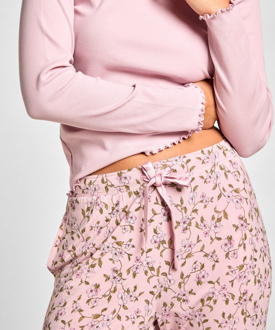 Dichtbij van een roze pyjamabroek met bloemenprint en strikdetail.