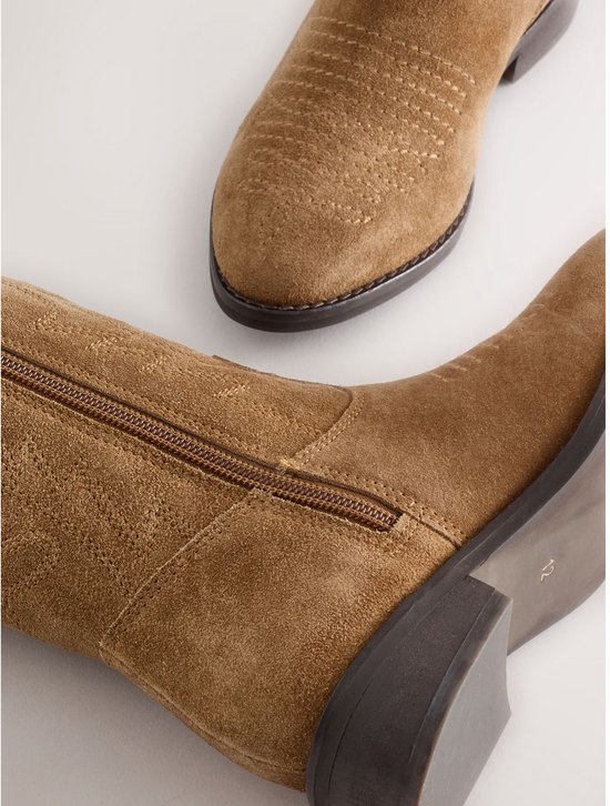 Detailopname van een bruine suède cowboylaars met zijrits en stiksel op de schacht.