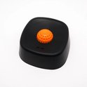 Zwarte voerbak met een oranje knop in het midden en twee kleine gaatjes.