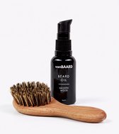 Zwarte fles van vanBAARD met baardolie, met de tekst BEARD OIL SMOOTH WOOD. Naast de fles ligt een houten baardborstel met bruine borstelharen.