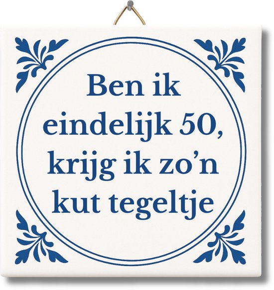 Wit tegeltje met Delfts blauwe randdecoratie. In het midden staat de tekst: 'Ben ik eindelijk 50, krijg ik zo'n kut tegeltje'.