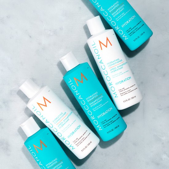 Drie flessen Moroccanoil Hydrating Shampoo en twee flessen Hydrating Conditioner, wit met oranje logo en turquoise met witte tekst.