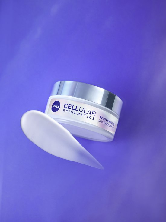 Een schepje NIVEA Cellular Epigenetics Dagcrème SPF 30 zweeft naast de pot op een paarse achtergrond.