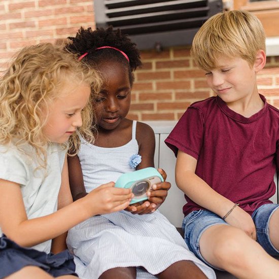 Drie kinderen kijken naar een cyaan Kidycam die een meisje vasthoudt.