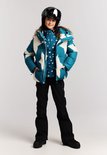 Meisje in blauwe winterjas met sterrenprint, onderlaag met sterren, zwarte skibroek en skihelm.