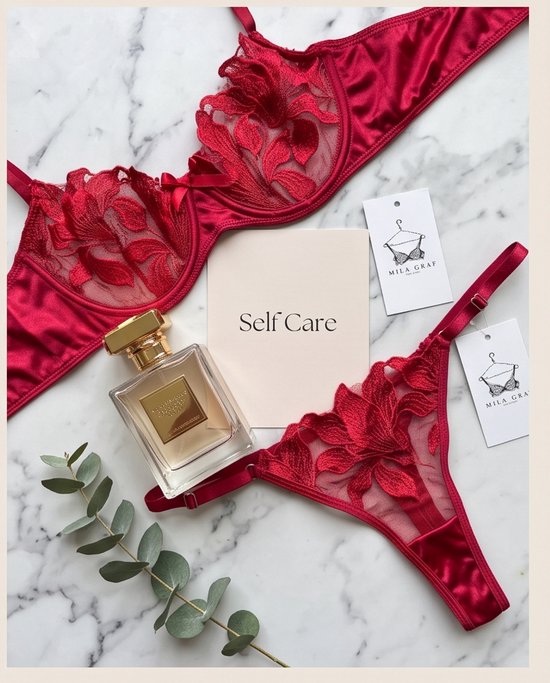 Dieprode kanten lingerieset met Mila Graf labels, parfum en kaartje met 'Self Care' op marmeren ondergrond.