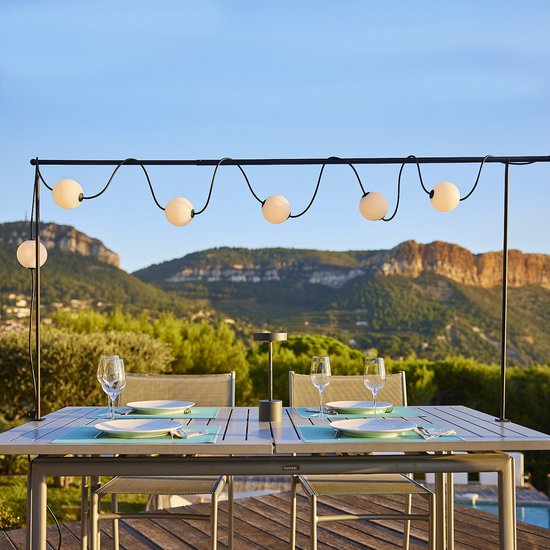 Decoratieve slinger met witte, ronde lampenkappen, opgehangen aan zwarte koorden.