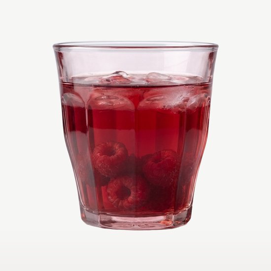 Un verre Duralex rose rempli d'une boisson rouge, de glace et de framboises.