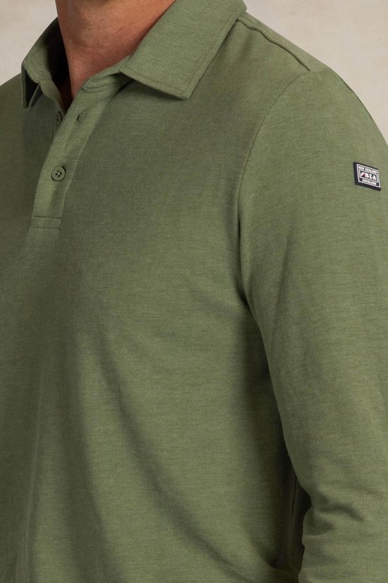 Close-up van een lichtgroen poloshirt met lange mouwen, met merklogo op de mouw.