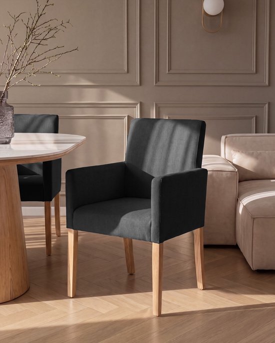 Chaise de salle à manger gris foncé avec rembourrage en tissu, pieds en bois, près d'une table à manger.