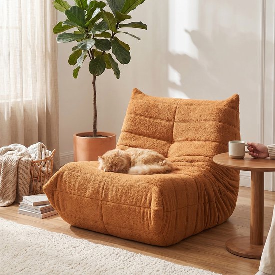 Slapende kat op een oranje pluche zitzak in een huiselijke setting.