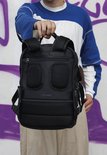 Zwarte New Rebels rugzak met mesh vakken en laptopvak voor 15,6 inch. Een man met een blauw-witte trui draagt de rugzak.