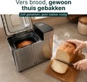Zilverkleurige broodbakmachine met een brood erin en een gesneden brood.