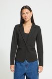 Model met lange zwarte blazer, één knoop sluiting, gedragen met een zwarte top en jeans.