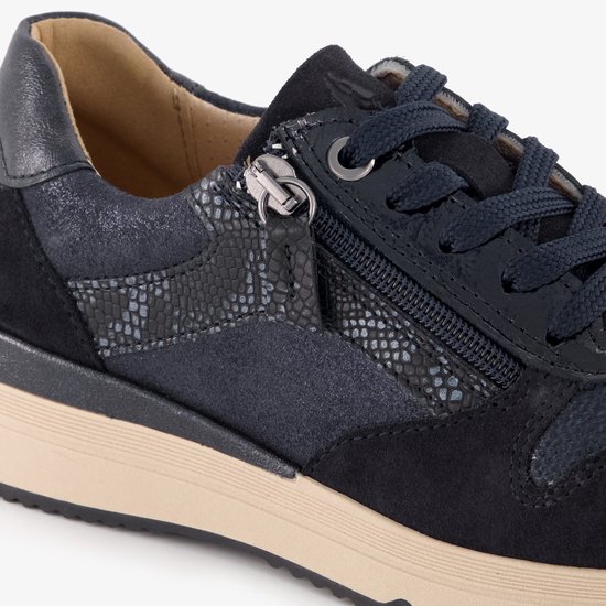 Detail van een donkerblauwe sneaker met suède, blauw reptielpatroon en ritssluiting.