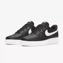 Zwarte leren Nike Air Force 1 sneakers met witte zolen, witte swooshes en witte hielen.
