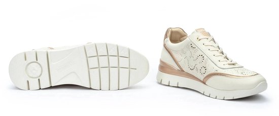 Sneaker Pikolinos en cuir écru perforé, accents dorés, fermeture éclair et lacets. Détails dorés métalliques sur le côté et le talon. La semelle est visible.