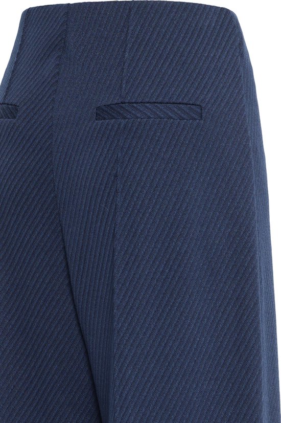Close-up van de achterzak en het diagonale textuurpatroon van de donkerblauwe broek.